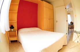 Quarto de casal com cama tipo box, ar-condiocionado e armário.